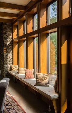 the sun shines through large windows into a room filled with couches and pillows