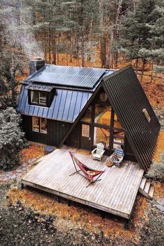 an aerial view of a small cabin in the woods with hammock and chairs