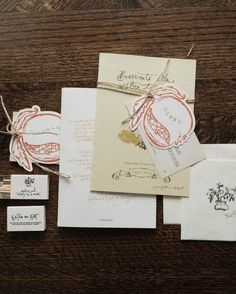 the wedding stationery is laid out on top of the wooden table, including envelopes and cards