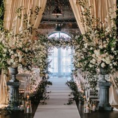 an aisle decorated with flowers and greenery for a wedding at the end of the aisle