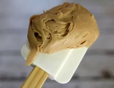 a wooden spoon filled with peanut butter on top of a white counter next to a brick wall