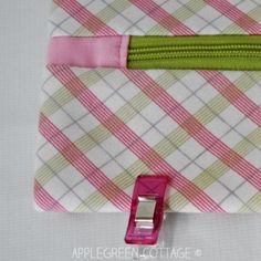 a pink and white checkered fabric with a green zipper