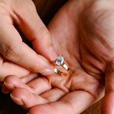 two hands holding an engagement ring on top of each other