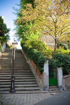 there is a green door at the bottom of this set of stairs that lead up to another building