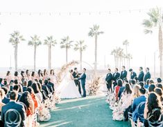 a couple getting married in front of an outdoor ceremony with palm trees and string lights