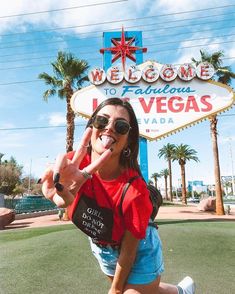 a woman posing in front of the welcome to fabulous las vegas sign with her hand up