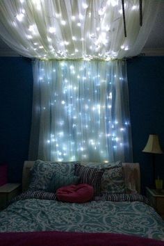 a bed sitting under a window covered in lights