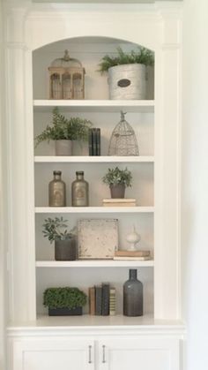 a white bookcase filled with lots of books next to a wall mounted planter