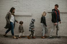 a group of people standing next to each other in front of a white brick wall