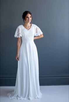 a woman in a long white dress posing for a photo with her hands on her hips