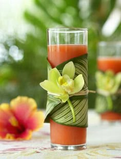 a glass filled with water and flowers on top of a table