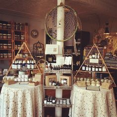 two tables with jars and candles on them in a room filled with shelves full of items