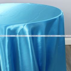 a blue table cloth on top of a round table in a room with hardwood floors