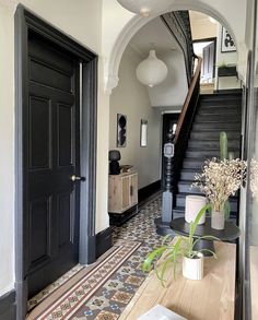 an entry way with black doors and decorative tiles on the floor, along with potted plants