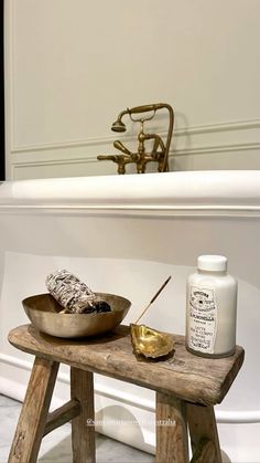 a wooden table with two bowls on it next to a bathtub and a brush