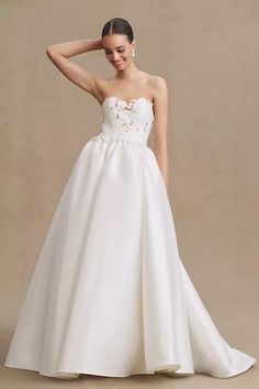 a woman in a white wedding dress posing for the camera with her hand on her head