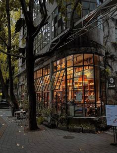 an old building is lit up at night with lights on the windows and people walking by