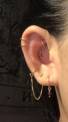 a close up of a person's ear with two gold chains attached to it