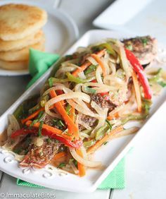 a white plate topped with meat and veggies on top of a green napkin