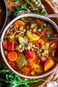 a bowl of soup with carrots, zucchini and other vegetables