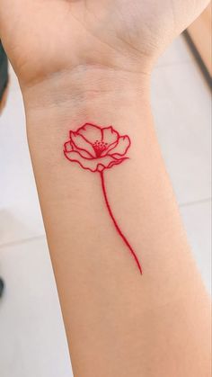 a woman's wrist tattoo with a red flower on the left side of her arm