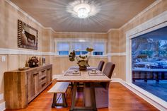 a dining room table with two chairs and a bench in front of a large window