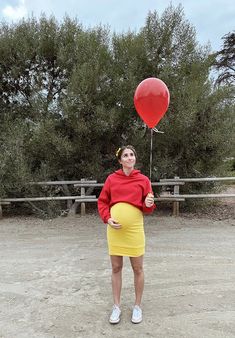 a woman in a red shirt and yellow skirt holding a balloon