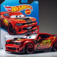 a red car with flames on the front and sides, next to a package for hot wheels