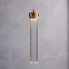 a glass and brass pendant light hanging from a ceiling fixture with a white wall in the background