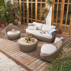 an outdoor living area with wicker furniture and potted plants on the decking