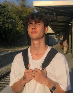 a young man standing in front of a train station with his hands folded and looking up