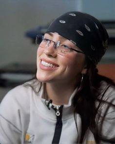 a smiling woman wearing glasses and a black hat