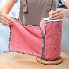 a woman is holding a pink towel on top of a wooden table