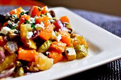 a white plate topped with vegetables on top of a blue table cloth next to a fork