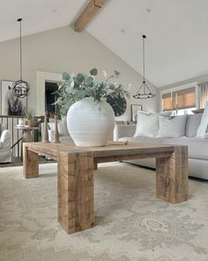 a large white vase sitting on top of a wooden table in front of a couch