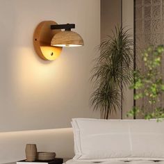 a white bed sitting next to a wall mounted light on the side of a wall