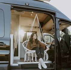 a woman sitting on a chair in the back of a van