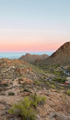 the sun is setting in the desert with mountains and cacti on the side