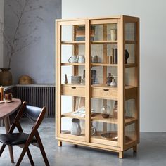 a wooden bookcase with glass doors and shelves on the front is next to a dining room table