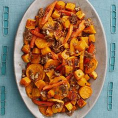 a white plate topped with cooked carrots on top of a blue table cloth next to utensils