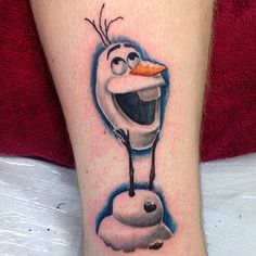 a cartoon character tattoo on the leg of a person with an orange slice in it's mouth