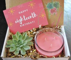 a pink candle and some succulents in a box with a happy birthday card