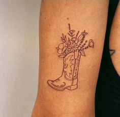 a tattoo on the arm of a woman with boots and flowers