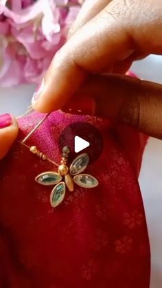 a person is stitching something on to a red bag with flowers in the background