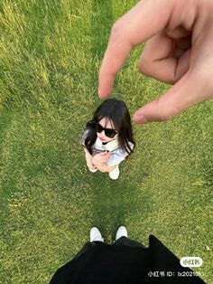 two people standing in the grass looking at a small doll