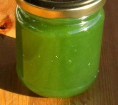 a jar filled with green liquid sitting on top of a wooden table