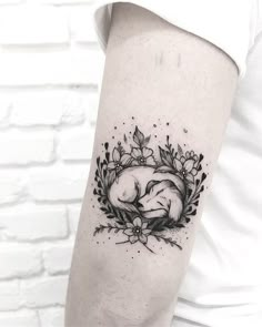 a woman's arm with a black and white tattoo of a sleeping dog on it