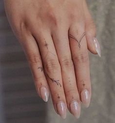 a woman's hand with two small tattoos on her left thumb and one finger