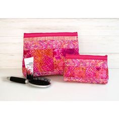 three cosmetic bags, one with a brush and the other has a zippered pouch