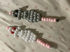 two toy animals made out of beads laying on a bed with pink and white polka dots